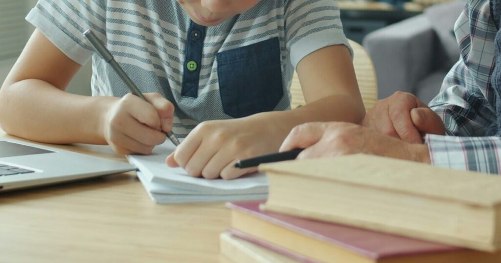 勉強を教える父親と、横で一生懸命問題を解いている男の子